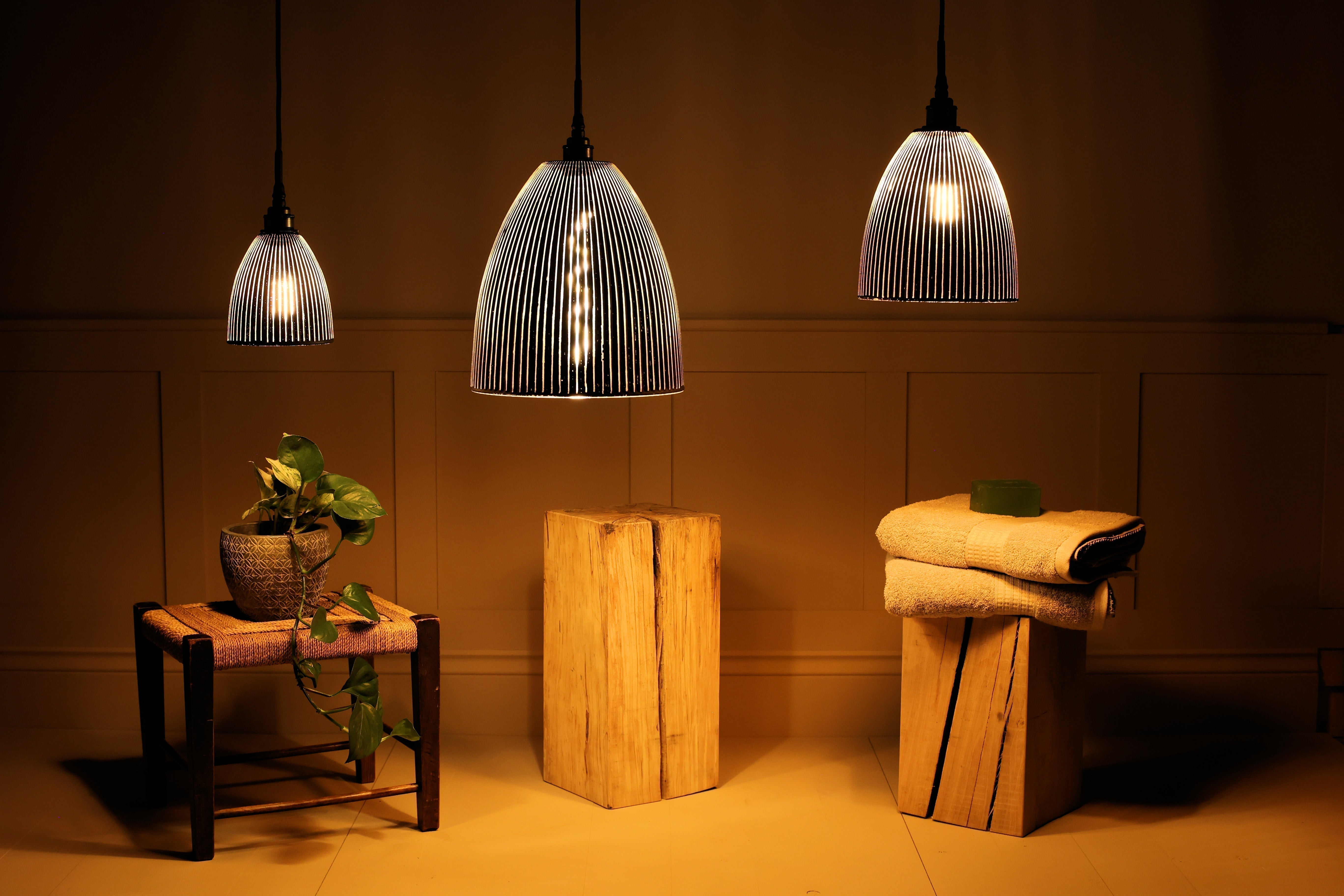 Cluster of 3 black and gold bathroom pendant lights hanging over table and towels
