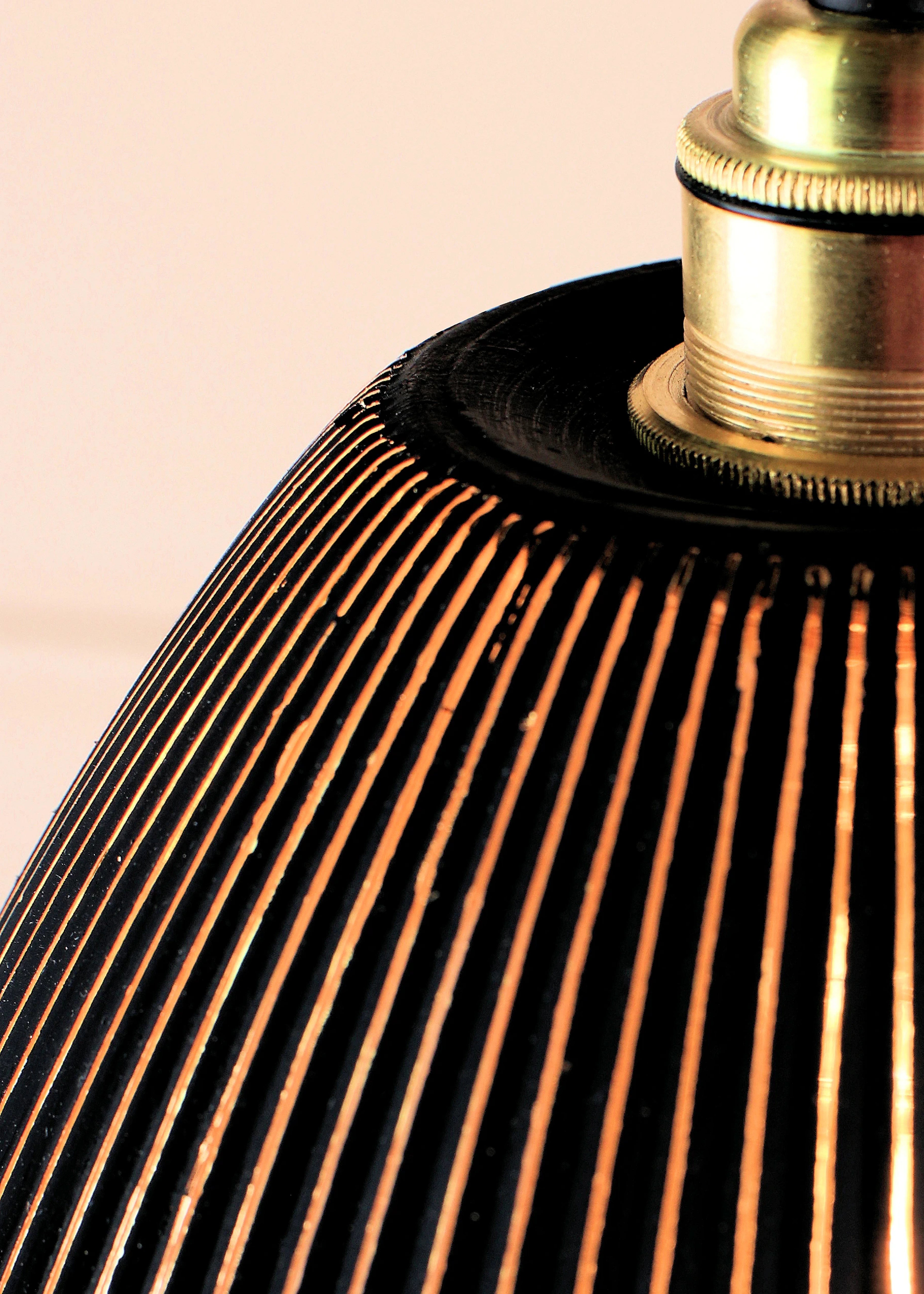Close-up of a lampshade with a ribbed design and brass fitting on a beige background
