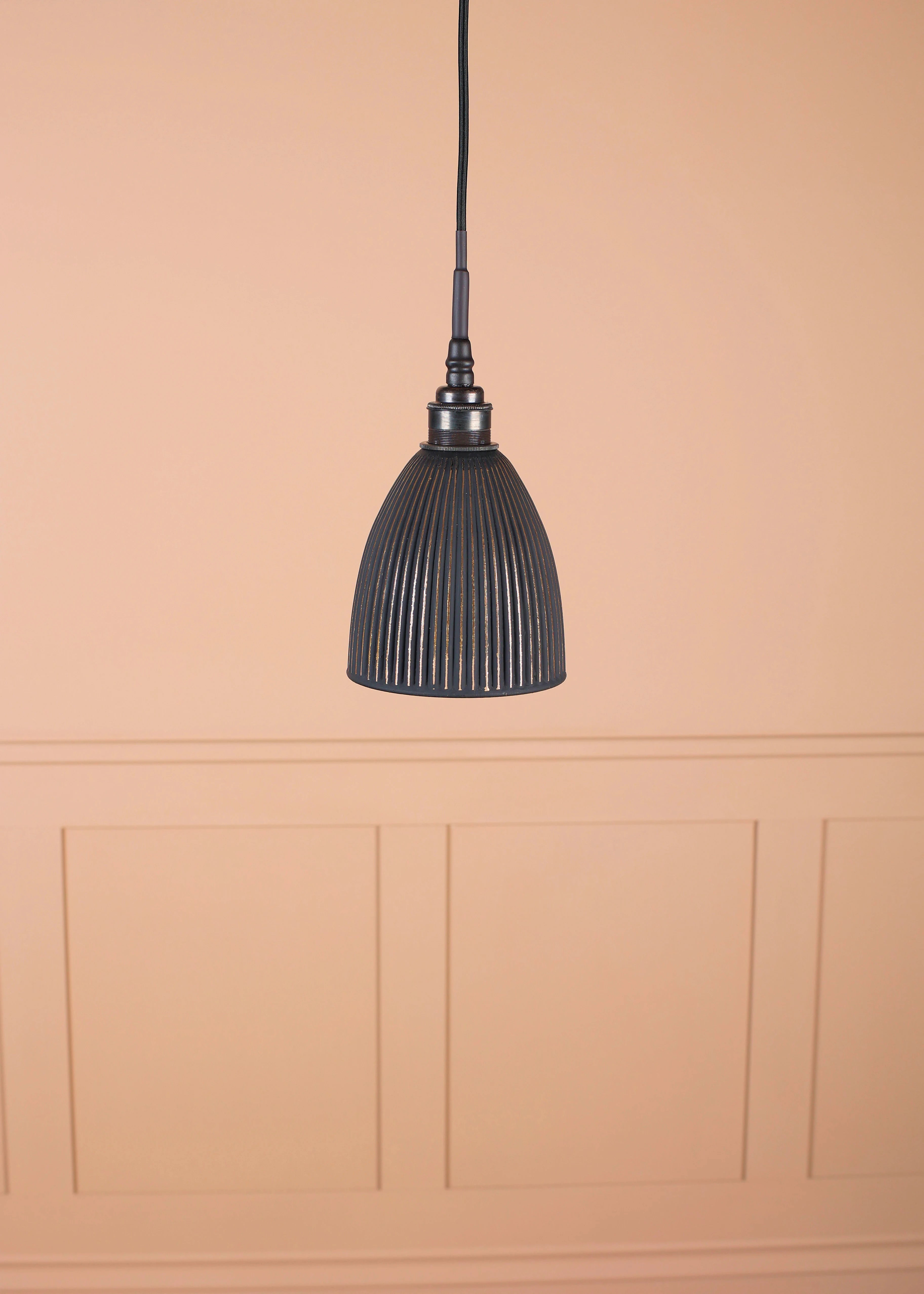 Black & gold bell shaped bathroom pendant light with bronze lamp holder on tan coloured panelled background