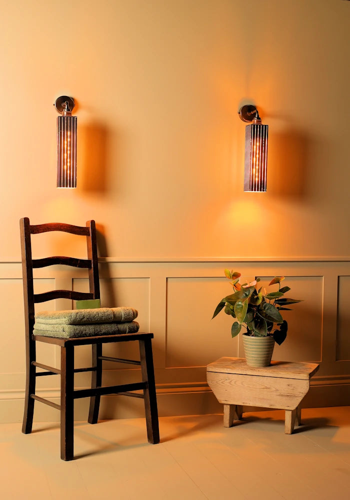 Elegant black and gold IP44 bathroom wall lights, wooden chair with towels, plant