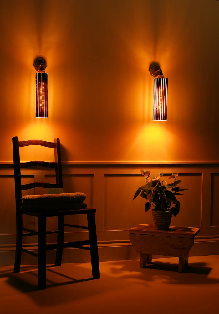 Elegant black and gold IP44 bathroom wall lights, wooden chair with towels, plant