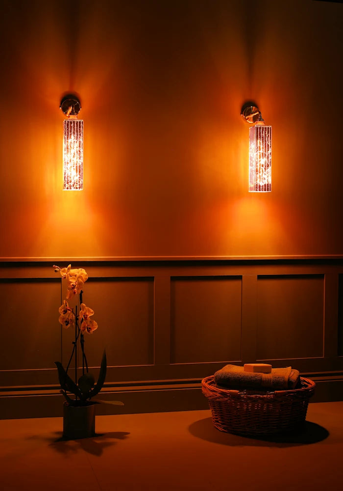 Elegant copper IP44 bathroom wall lights, basket of bath towels, exotic plant