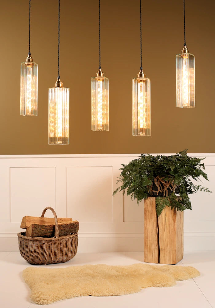 Five pendant lights hanging from the ceiling with a plant and basket on the floor.