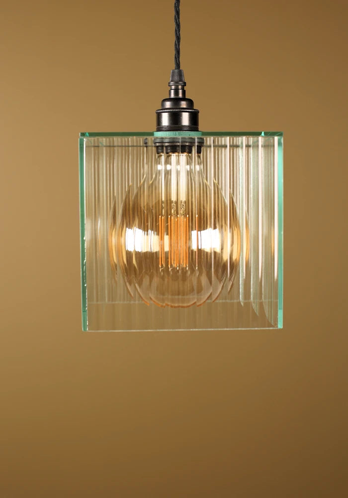 Glass pendant light with bronze fixture on a beige background