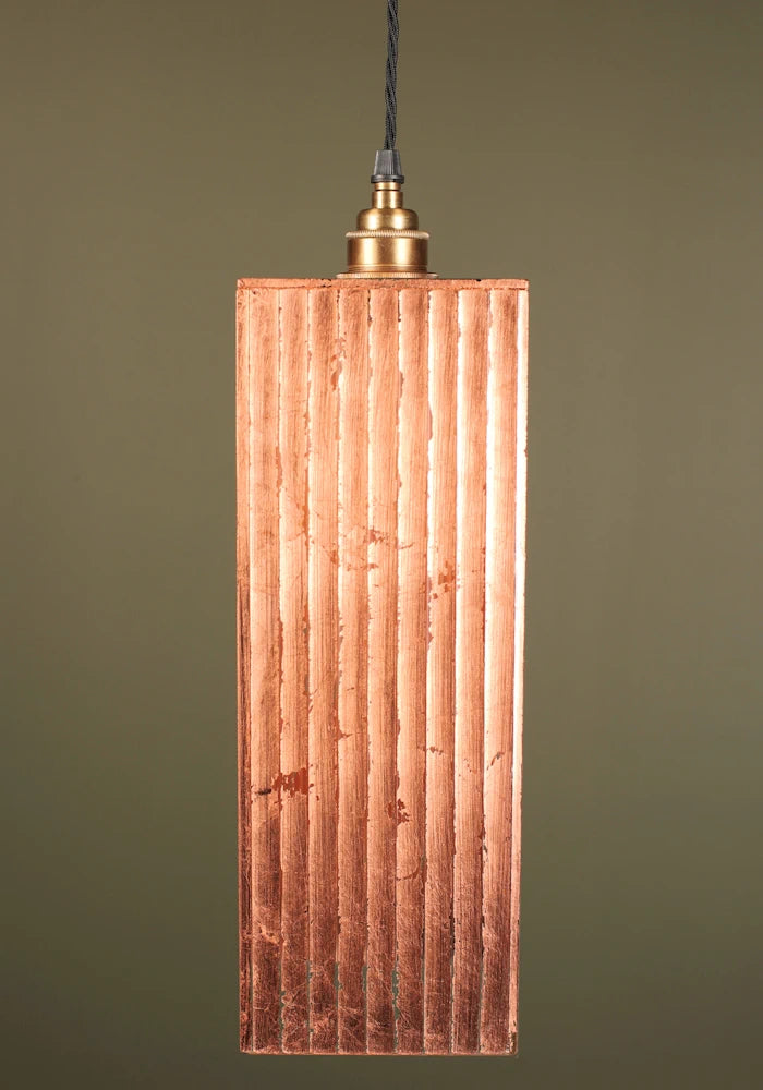 Copper pendant light with a ribbed design, brass lamp holder on a green background