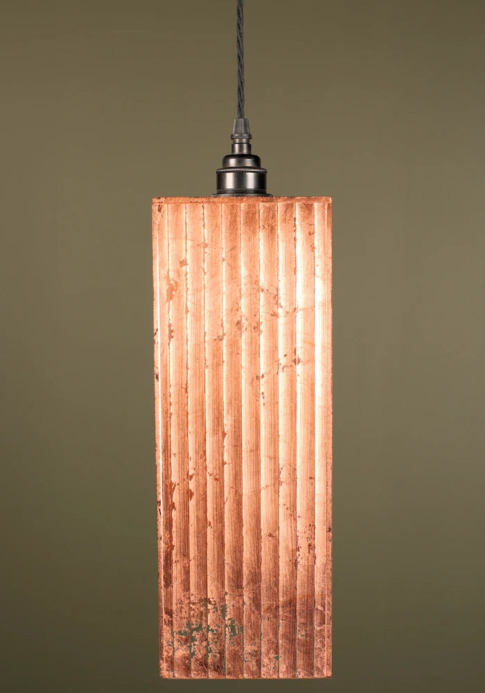 Copper pendant light with a ribbed design, bronze lamp holder on a green background