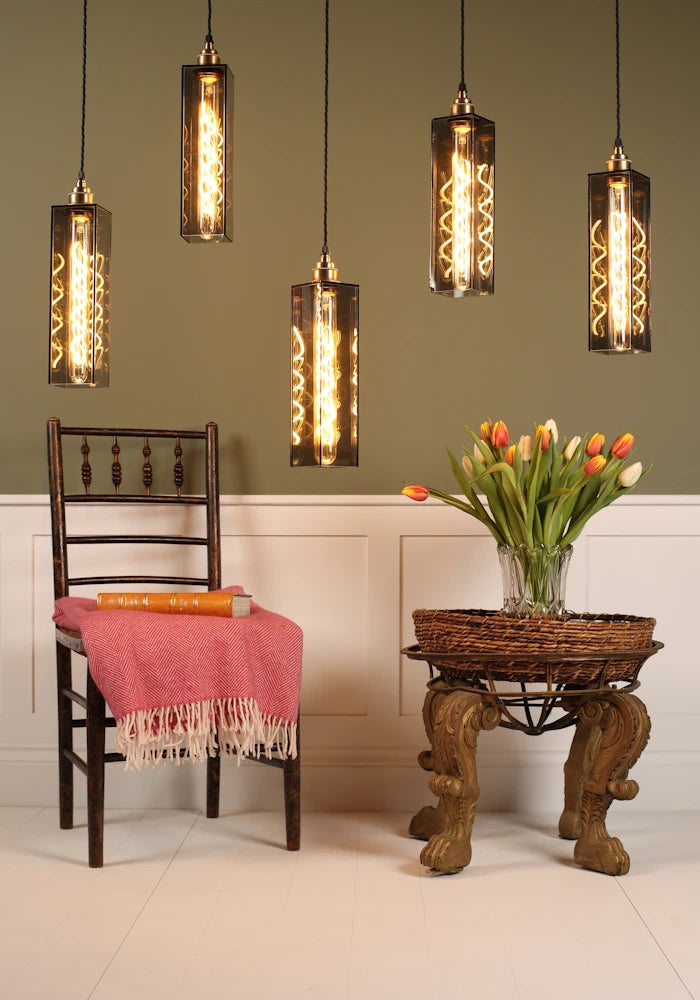 Decorative pendant lights hanging above a chair with a pink blanket and a small table with flowers.