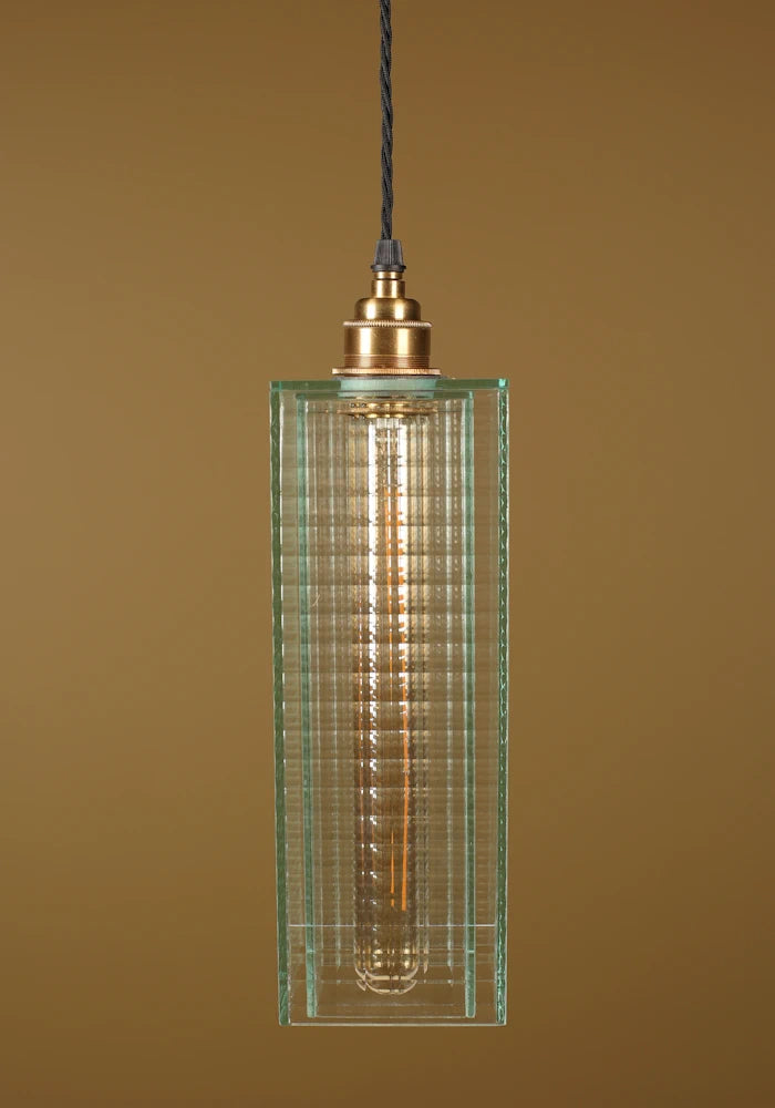 Pendant light with a green glass shade, brass lamp holder on a brown background