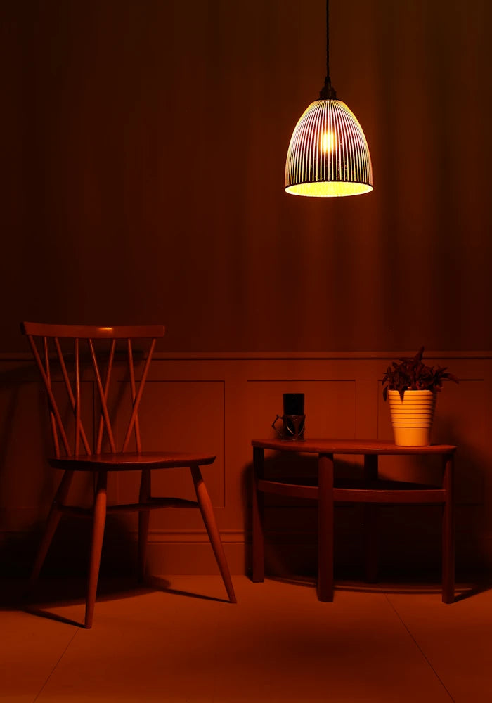 Dimly lit room with a pendant light, chair, and small table against a dark wall.