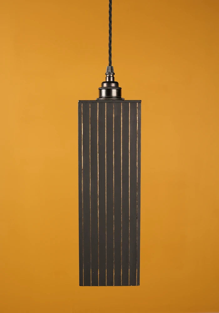 Pendant light fixture with ribbed design on a mustard yellow background with antique bronze lamp holder