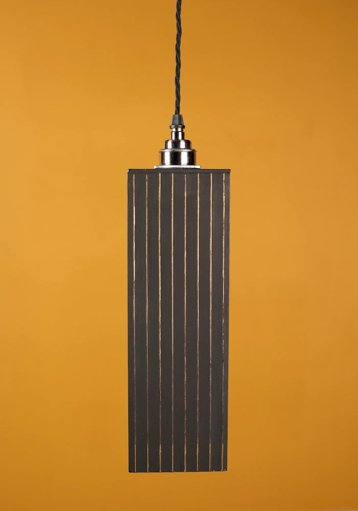 Pendant light with ribbed design on a mustard yellow background with nickel lamp holder