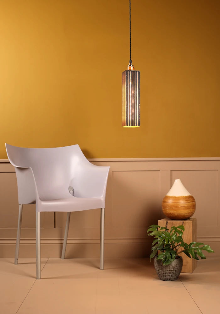 Modern interior with a pendant light, chair, and decorative items against a mustard yellow wall.