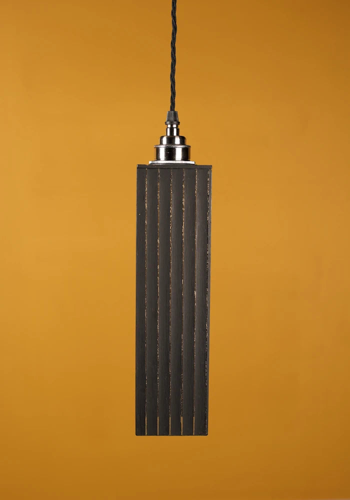 Pendant light with textured black shade against a mustard yellow background with nickel lamp holder
