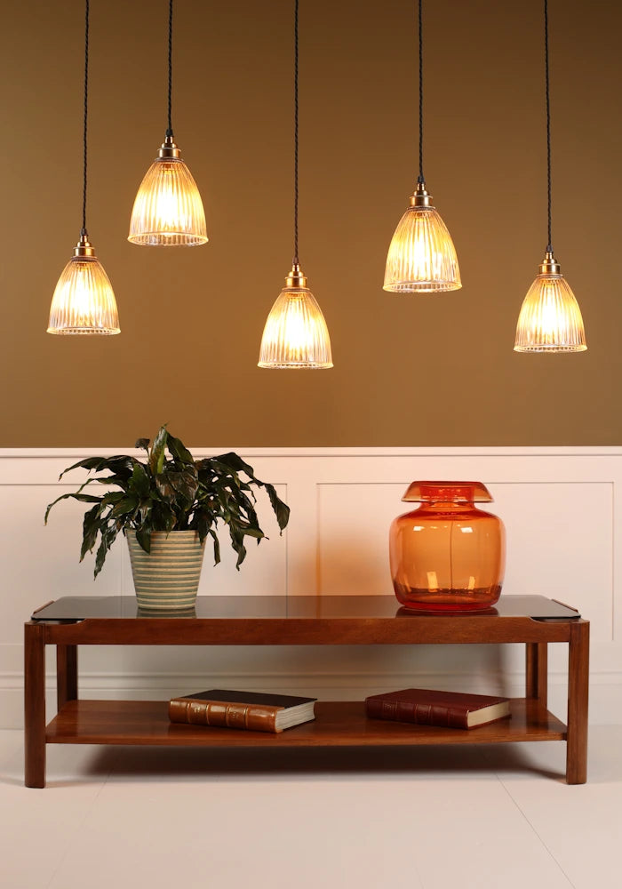 Cluster of prismatic glass pendant lights hanging over coffee table with vase, plant with beige background