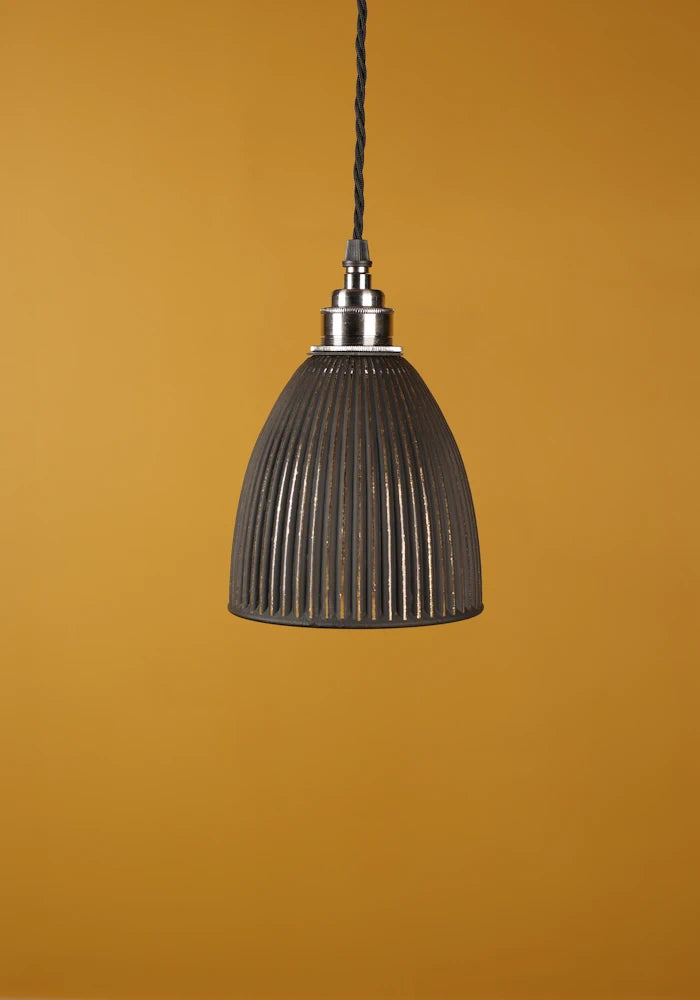 Black pendant light with nickel lamp holder against a mustard yellow background
