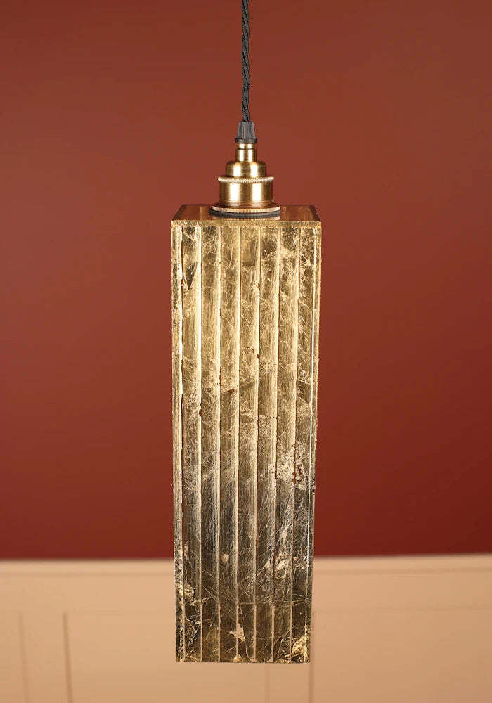 Pendant light with textured gold fixture, brass lamp holder against a red-brown background