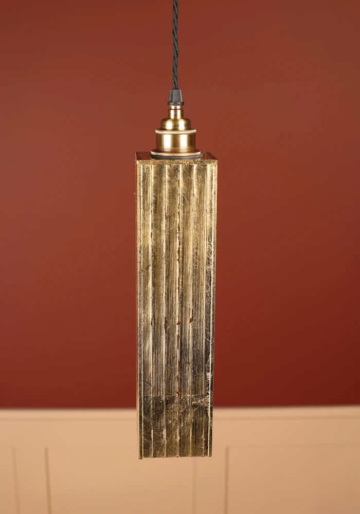 Pendant light fixture with textured design against a red wall with brass lamp holder