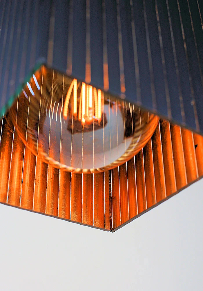 Close-up of a black pendant light with reflective gold surface