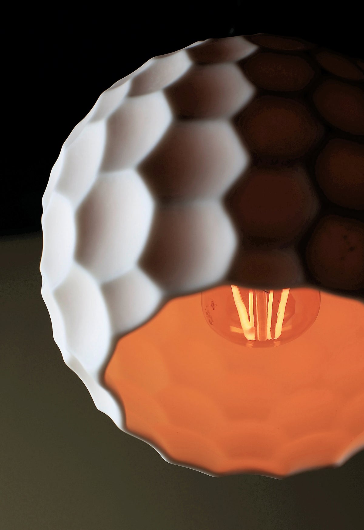 A close up of a ceramic beehive effect bathroom pendant light, glowing light bulb