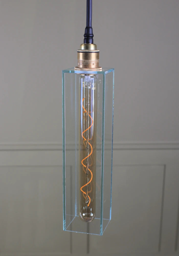 Long clear glass bathroom pendant light with brushed brass
lamp holder and black fabric flex.