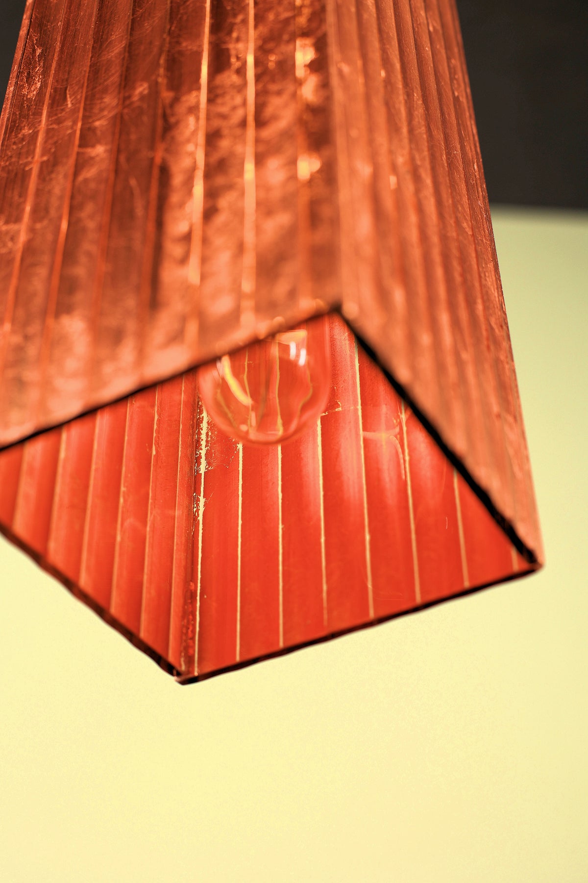 Close-up of a textured fluted glass copper pendant light on a yellow background