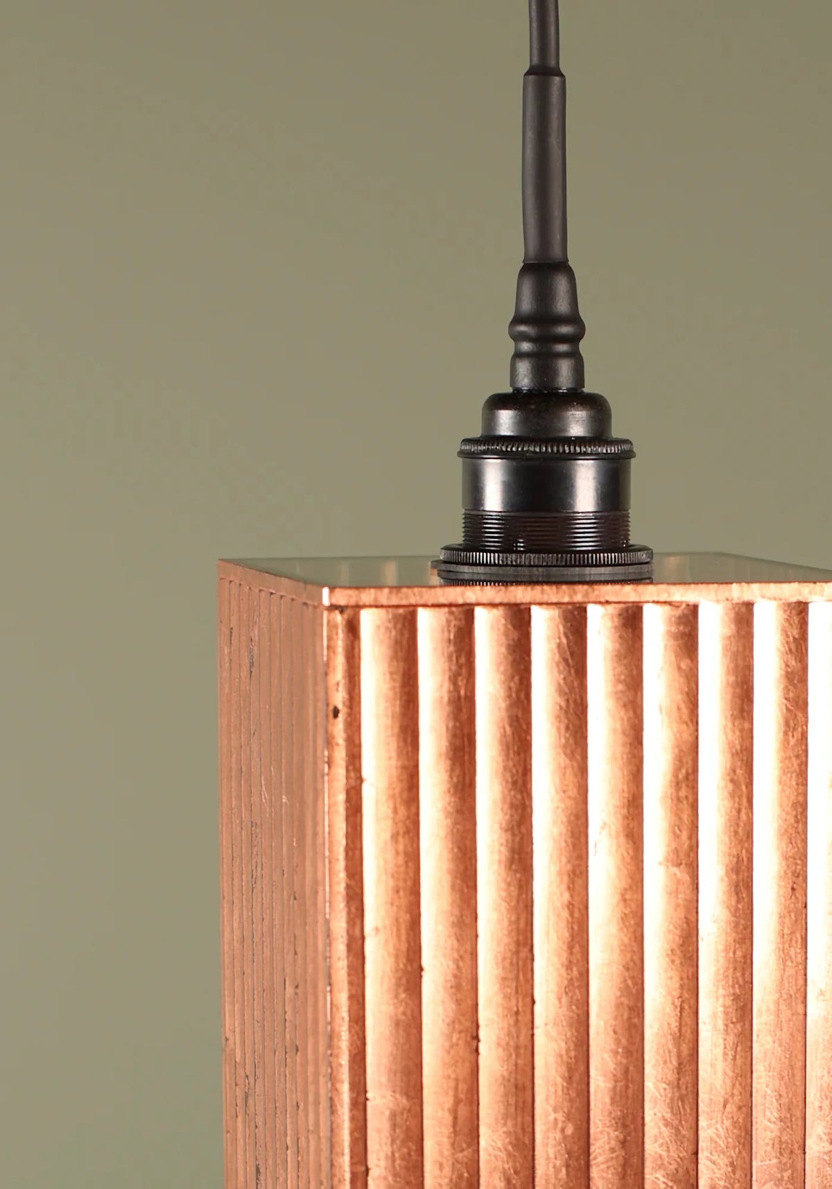 Close-up of a textured fluted glass copper pendant light on a green background