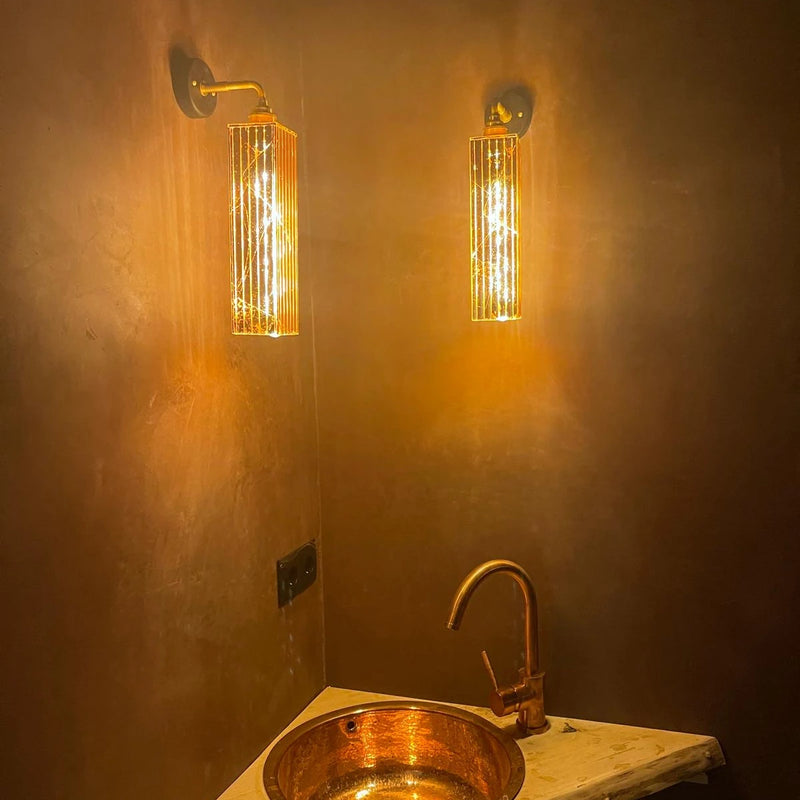 Bathroom with vintage-style gold wall lights, sink, and faucet.