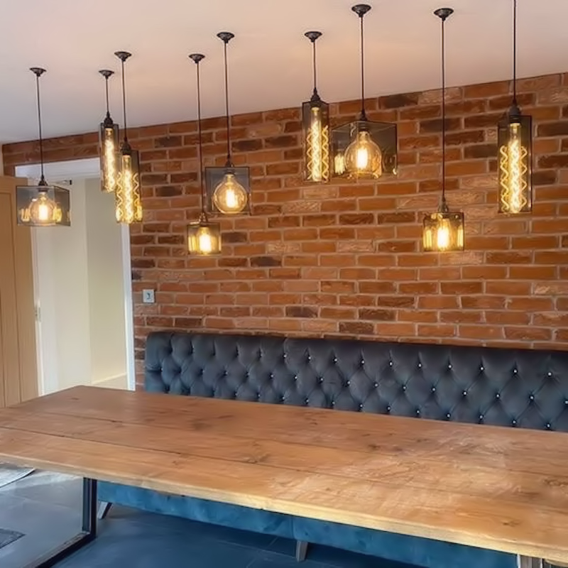 Multiple smoked glass pendant lights hanging over wooden dining table