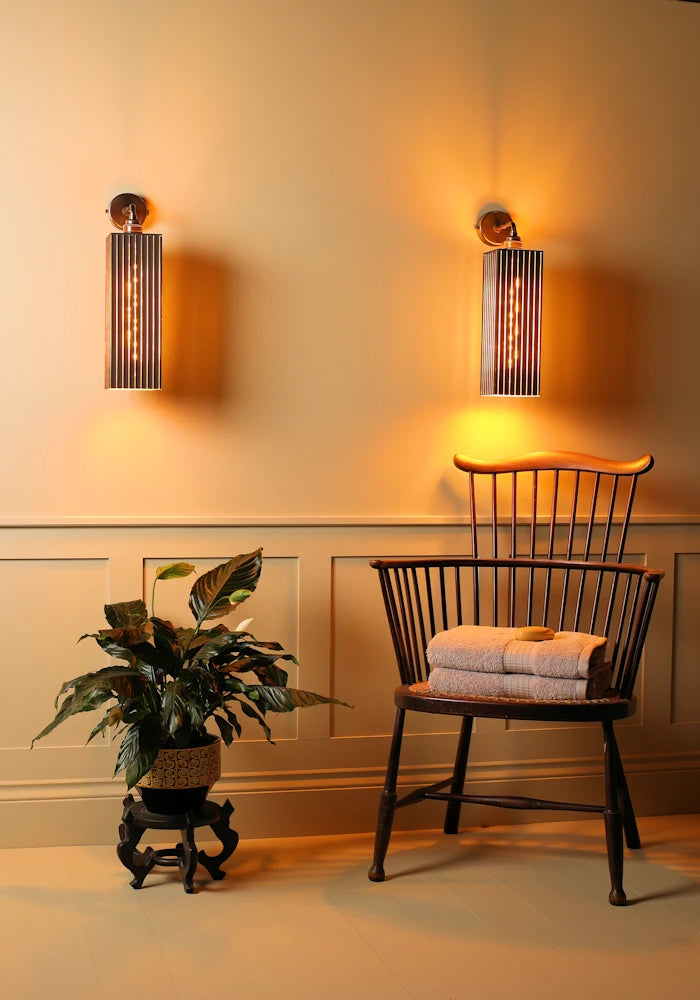 Elegant large black and gold IP44 bathroom wall lights, chair with towels and plant