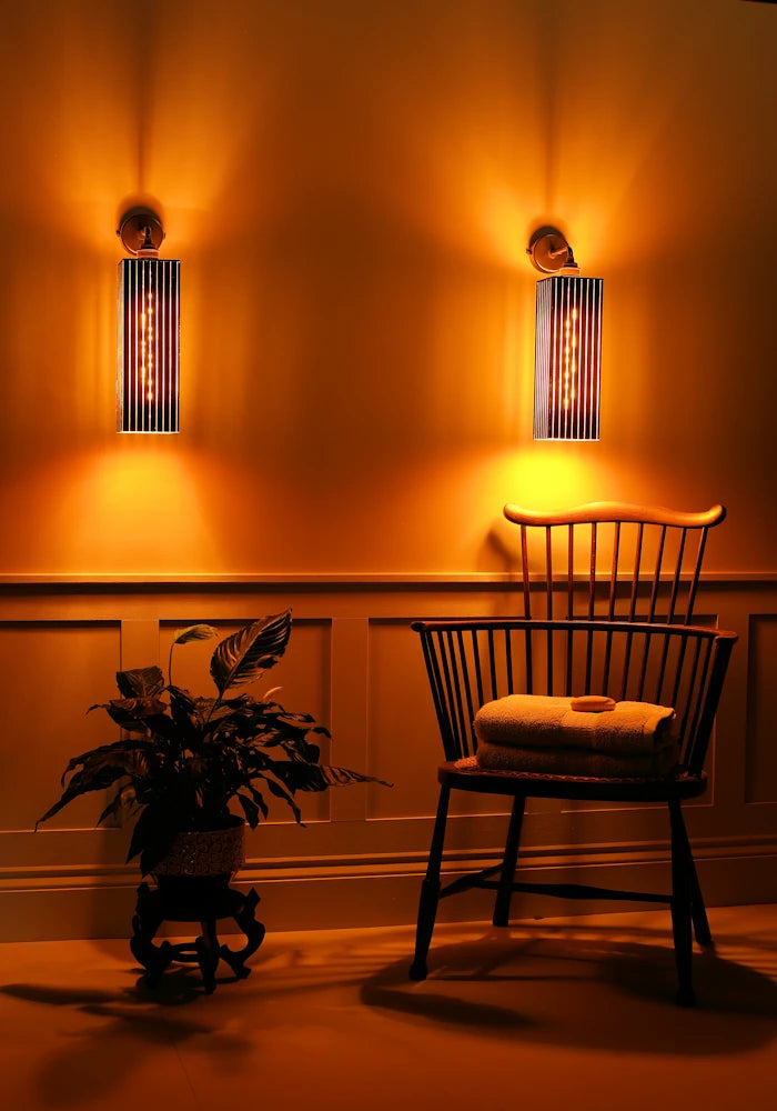 Elegant large black and gold IP44 bathroom wall lights, chair with towels and plant