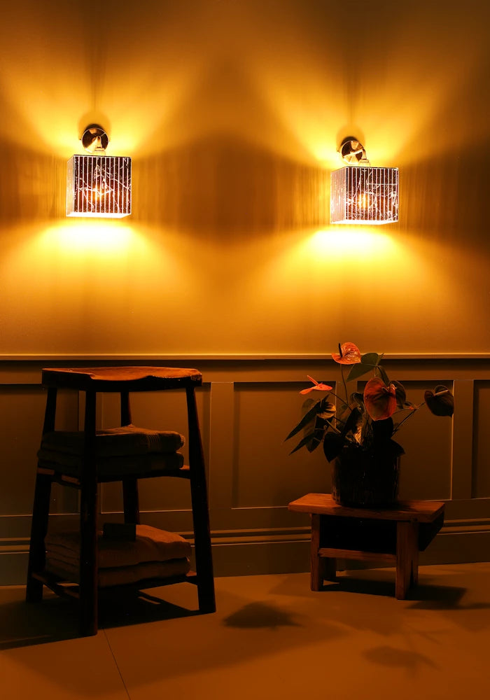 Elegant square silver leaf IP44 bathroom wall lights, wooden stool, bath towels pot plant