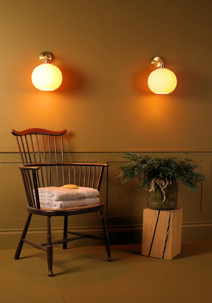Elegant round ceramic IP44 bathroom wall lights, vintage wooden chair with bath towels, pot plant