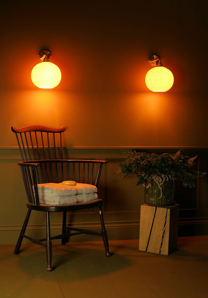Elegant round ceramic IP44 bathroom wall lights, vintage wooden chair with bath towels, pot plant