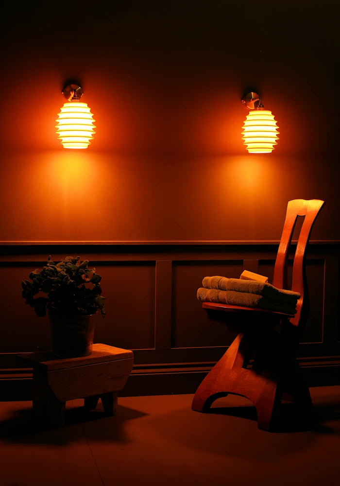 Elegant concertina style ceramic IP44 bathroom wall lights, pot plant, wooden chair with bath towels