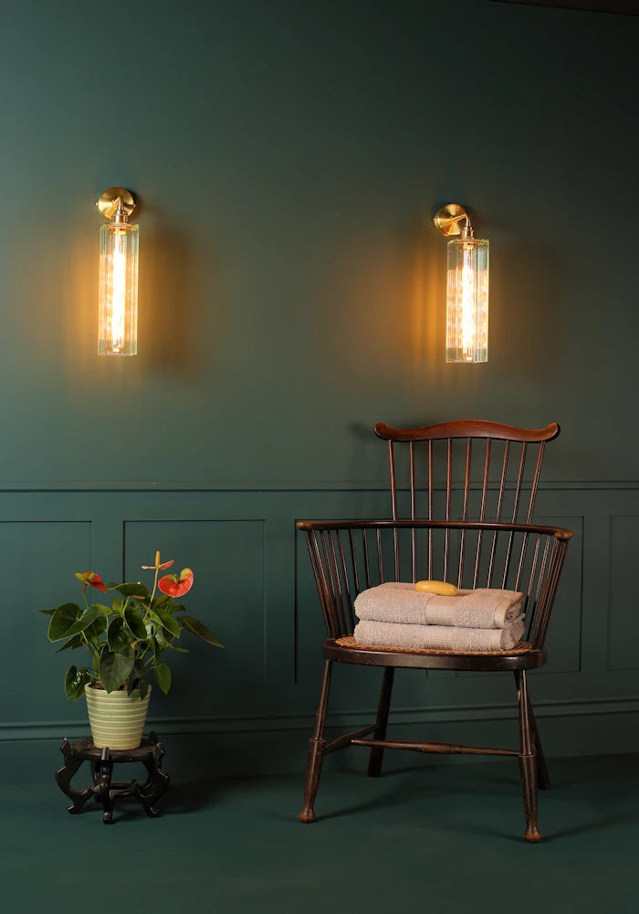 Elegant long fluted glass IP44 bathroom wall lights, exotic plant, vintage wooden chair with bath towels