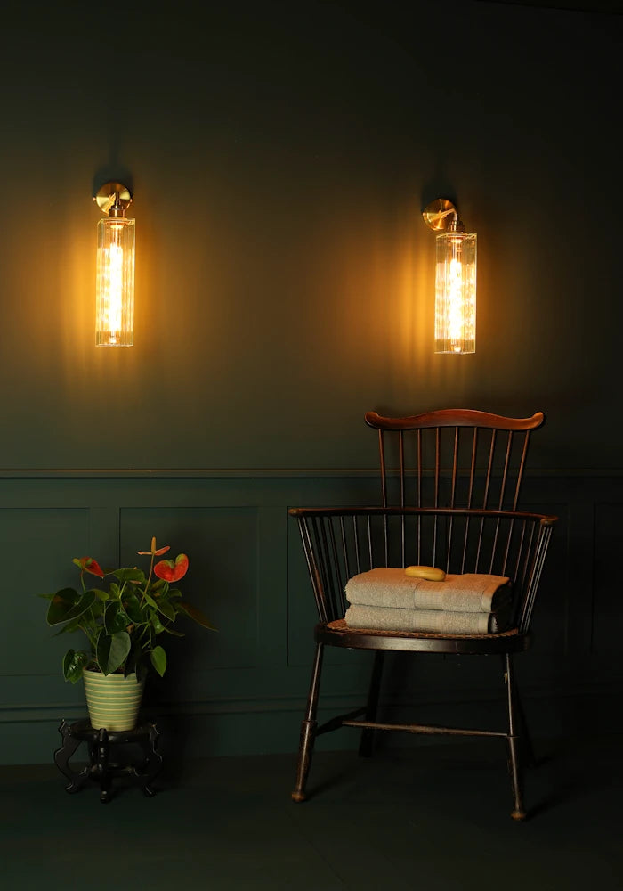 Elegant long fluted glass IP44 bathroom wall lights, exotic plant, vintage wooden chair with bath towels