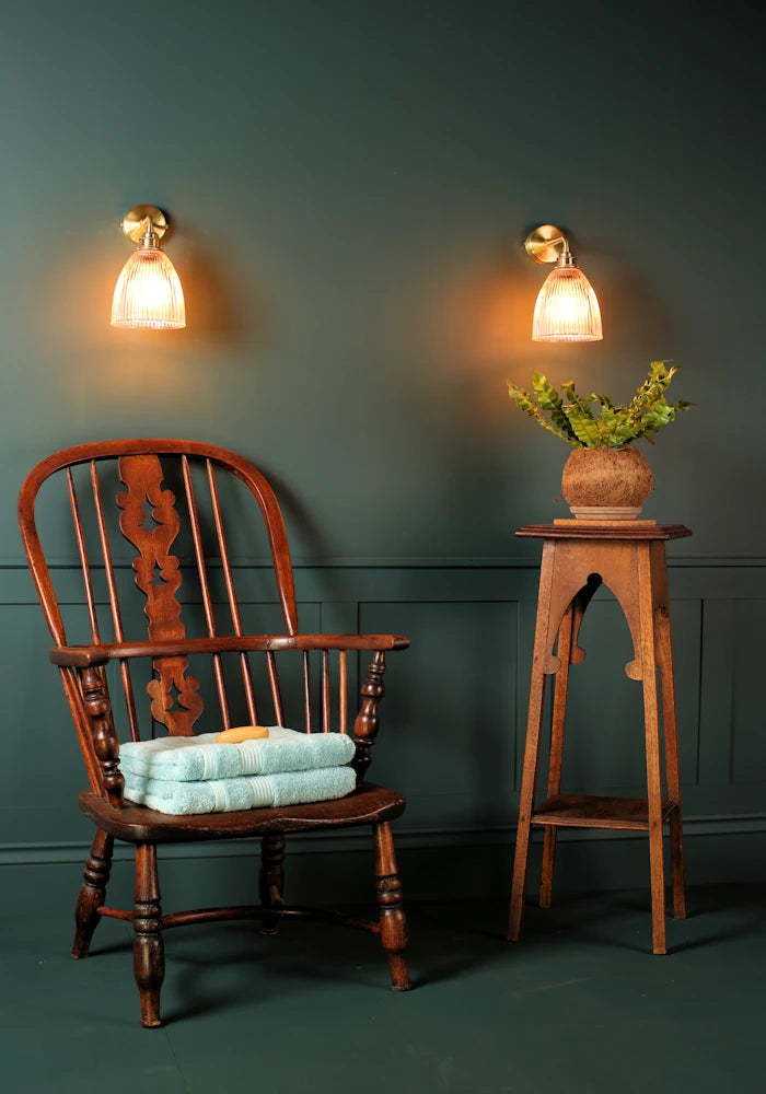 Elegant small bell glass IP44 bathroom wall lights, vintage wooden chair with bath towels, pot plant