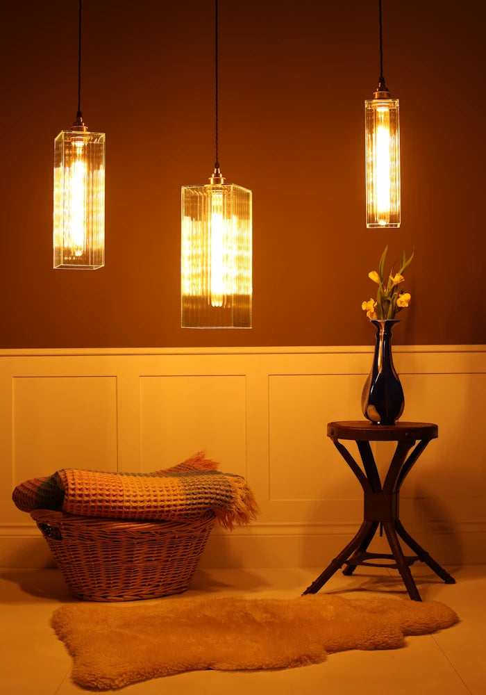 Three pendant lights hanging above a cozy living room with a basket, rug, and small table.