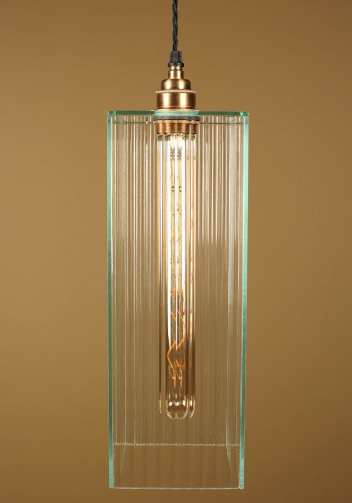 Fluted glass pendant light with glass shade, brass lamp holder on a brown background
