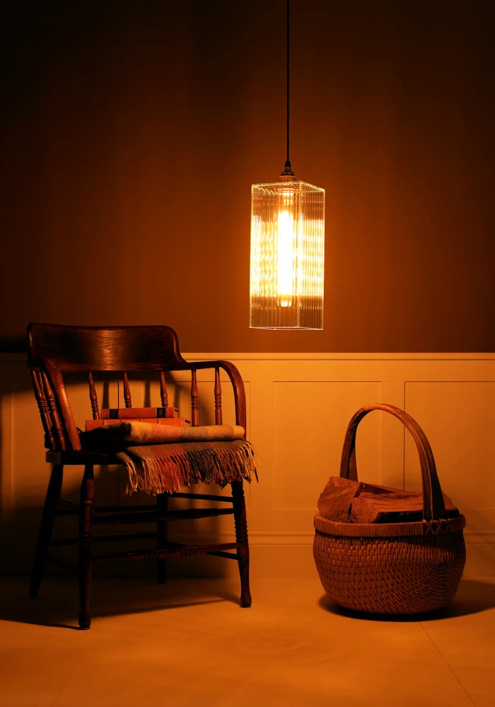Wooden chair with a woven basket on a wooden floor under a pendant light.