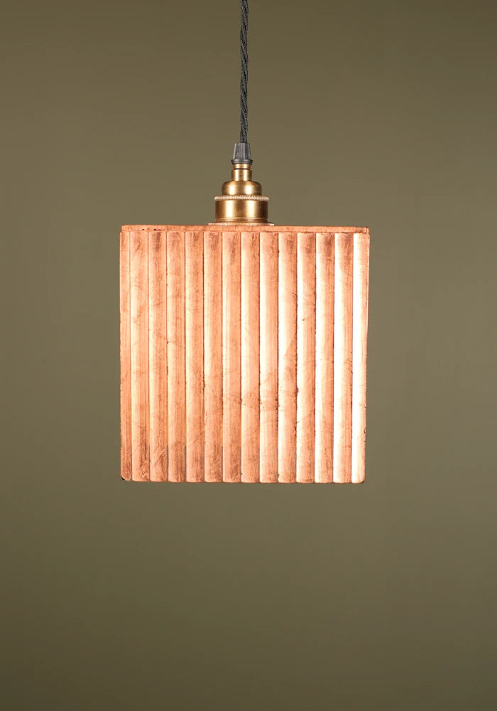 Square copper pendant light with brass lamp holder or a green background