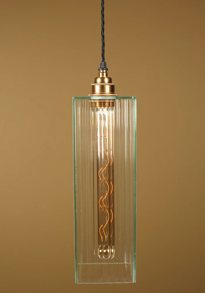 Pendant light with glass shade and brass fitting on a brown background