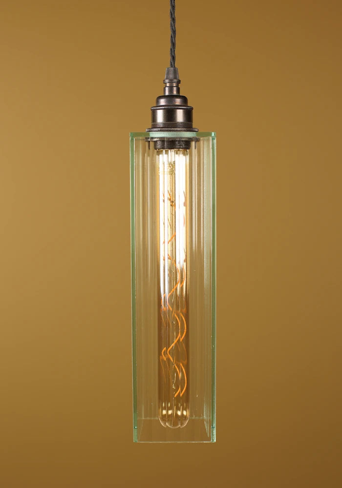 Pendant light with glass shade and visible bulb against a brown background