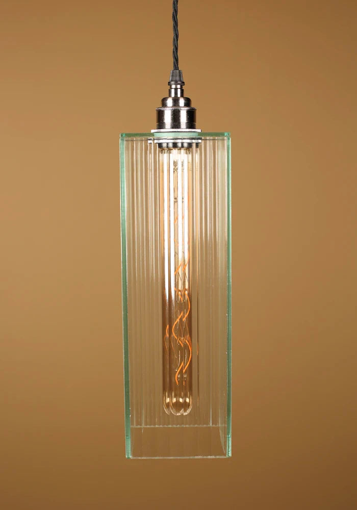 Glass pendant light with an exposed bulb, nickel lamp holder against a brown background