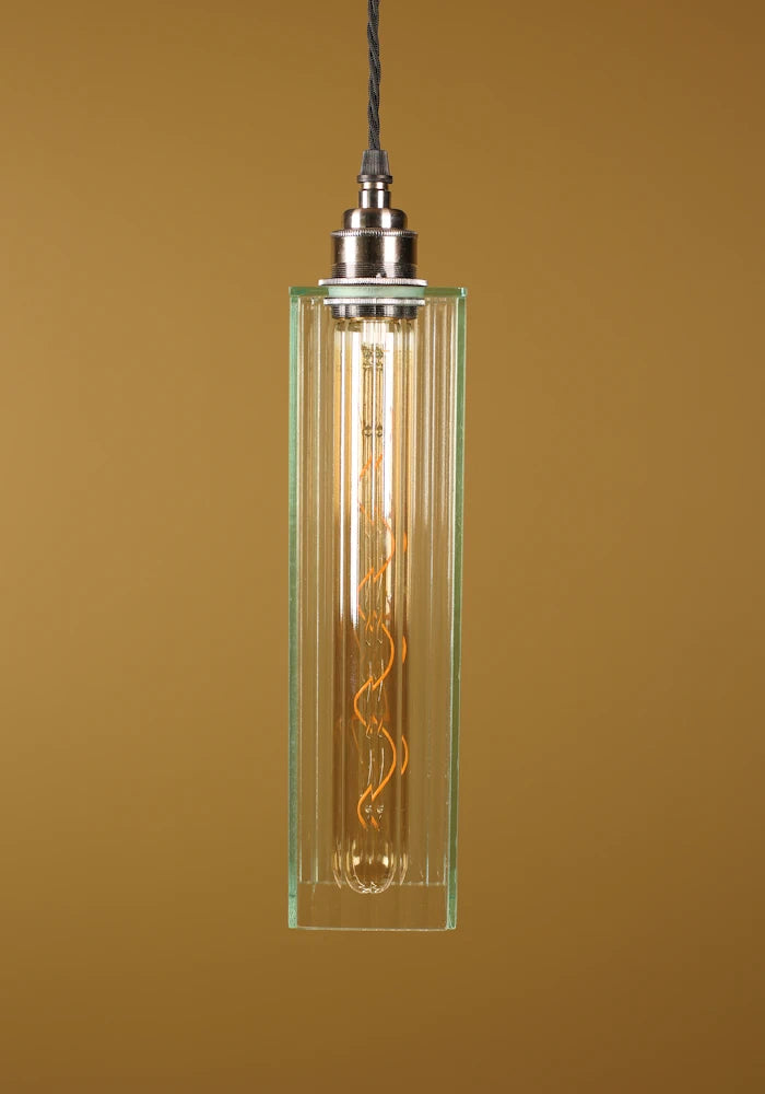 Glass pendant light with a visible bulb against a brown background