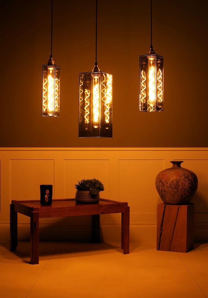 Three pendant lights hanging above a wooden table in a dimly lit room.