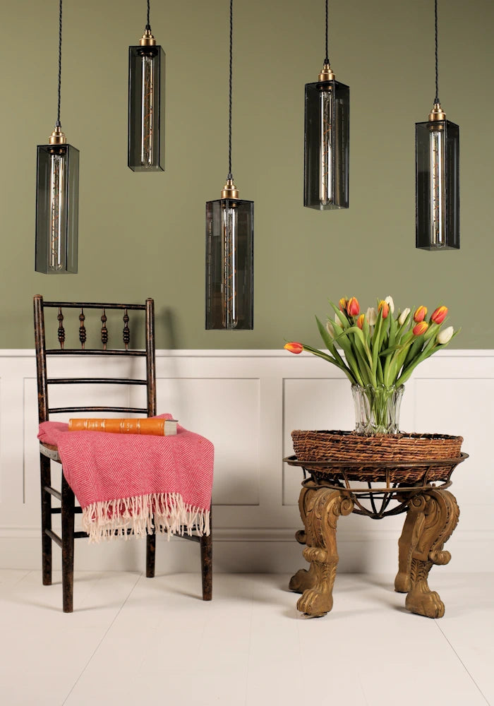 Dining room with wooden chair, table, and hanging pendant lights against a green wall.