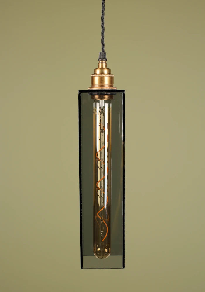 Smoked glass pendant light with brass lamp holder, exposed bulb on sage green background 