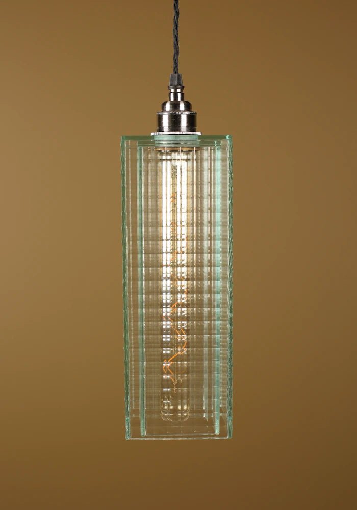 Pendant light with a green glass shade, nickel lamp holder on a brown background