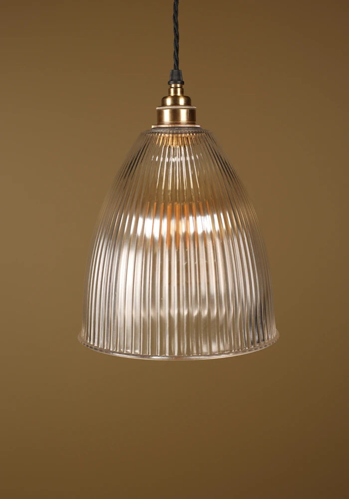 Bell shaped prismatic glass pendant light with brass lamp holder on beige background